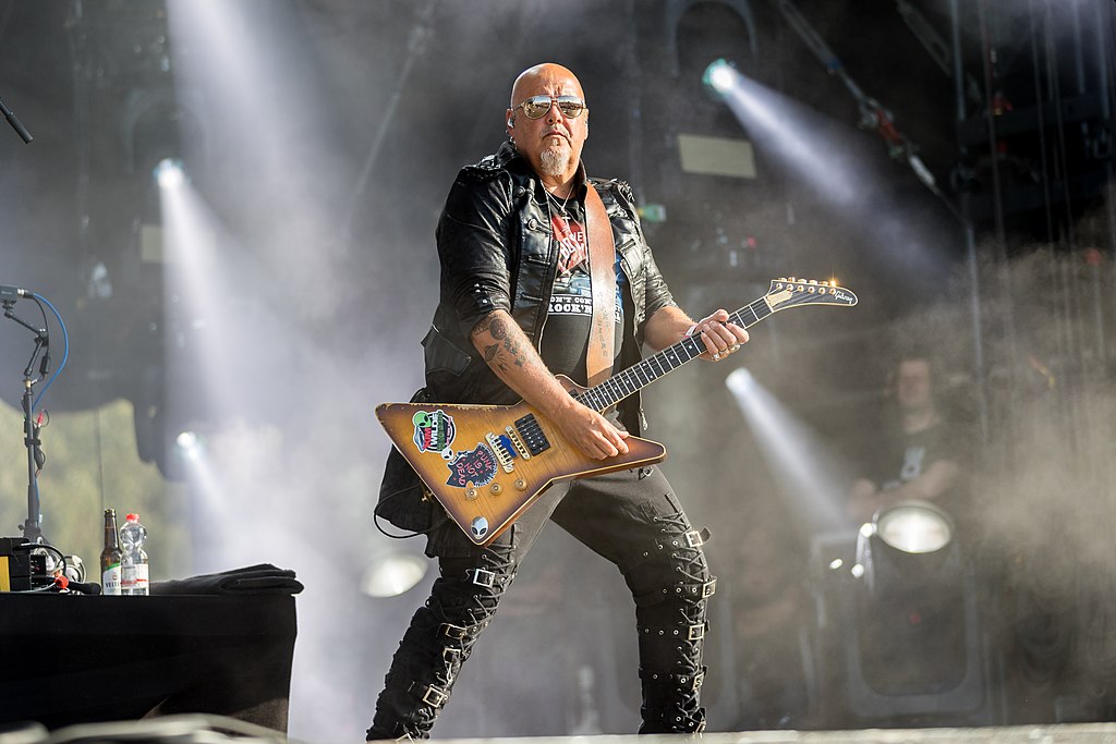 RIcky Wilde, em uma pose cyberpunk roqueira com guitarra.